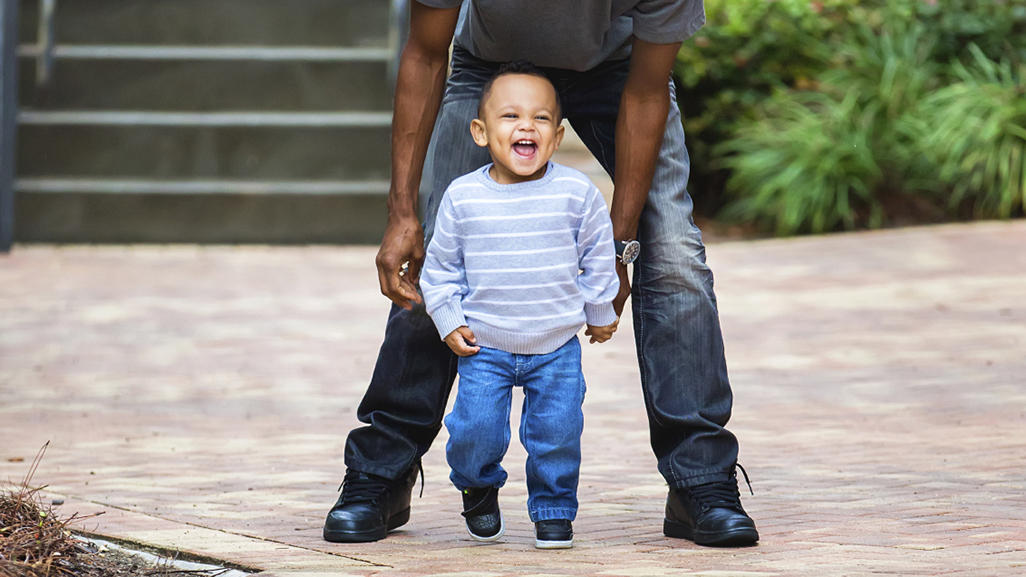 dad and young son smiling and walking