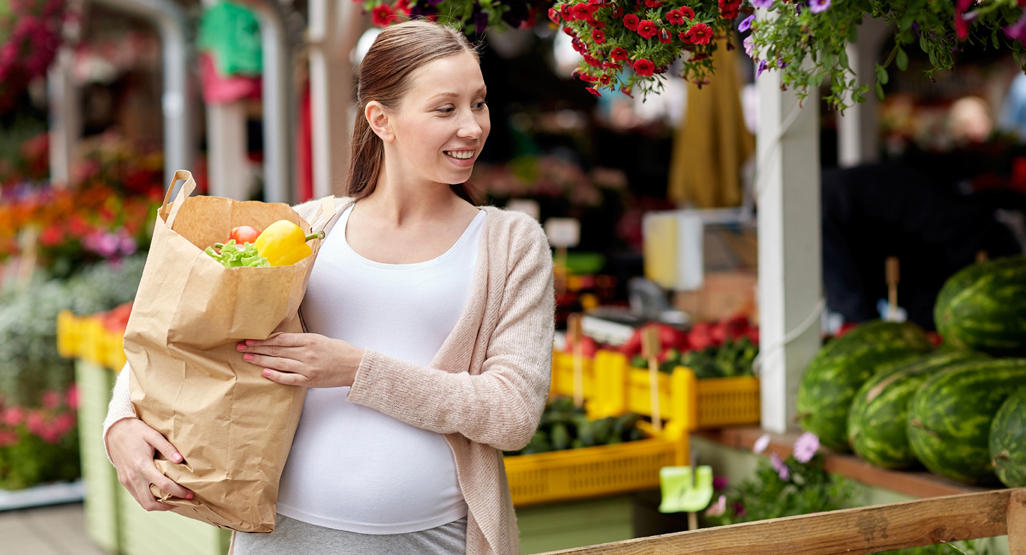 pregnant woman at outdoor market picking vegetables