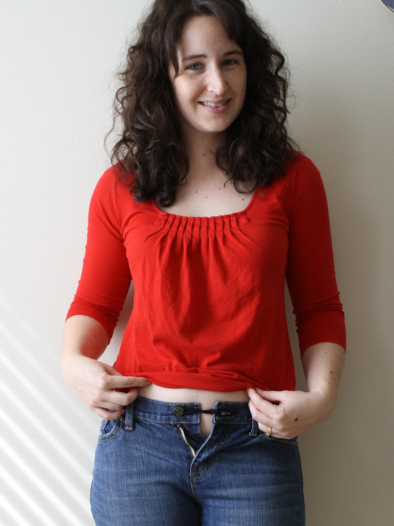 woman whose pants are buttoned using a rubber band to expand over pregnant stomach