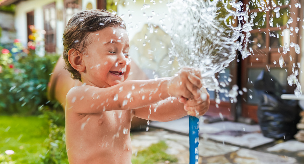  young child playing in water hose