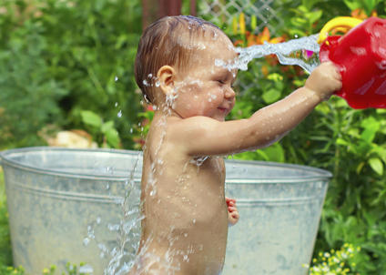 toddler playing outside with a bucket of water