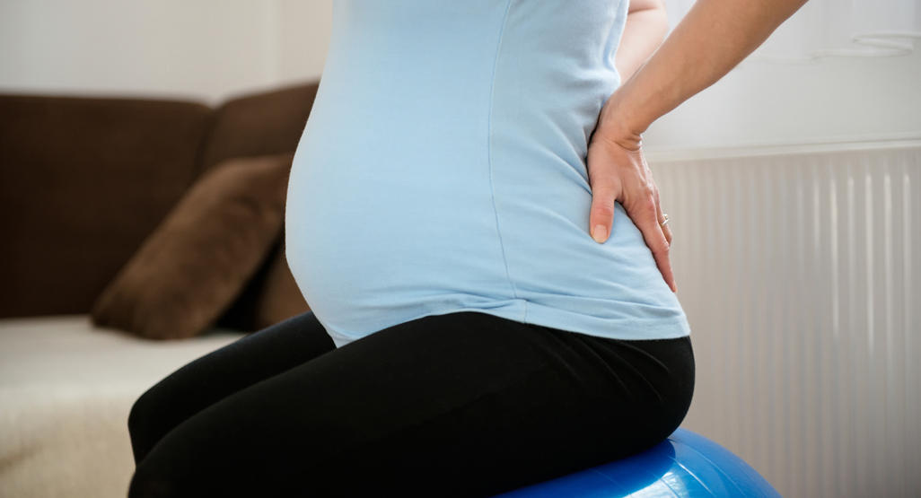 pregnant woman pushing on her own back