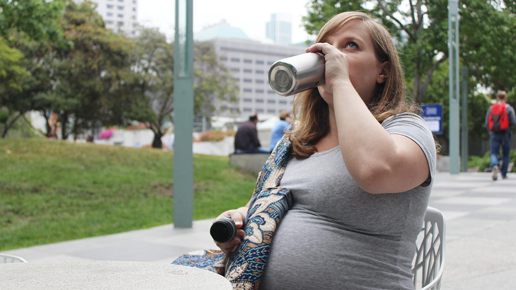 pregnant woman drinking from aluminum water bottle