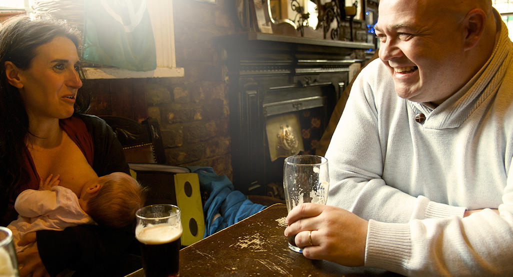 woman breastfeeding while having a beer in a pub