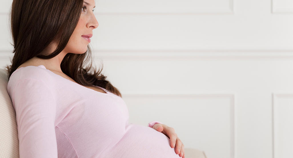 pregnant woman with hand on belly looking off into the distance
