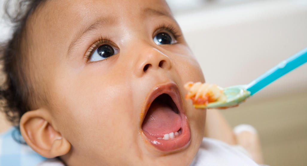 baby looking up with mouth open while being fed