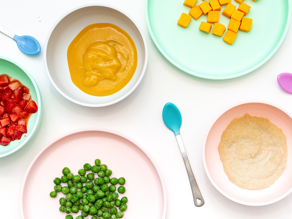 tablescape with various colored baby foods and purees on plates
