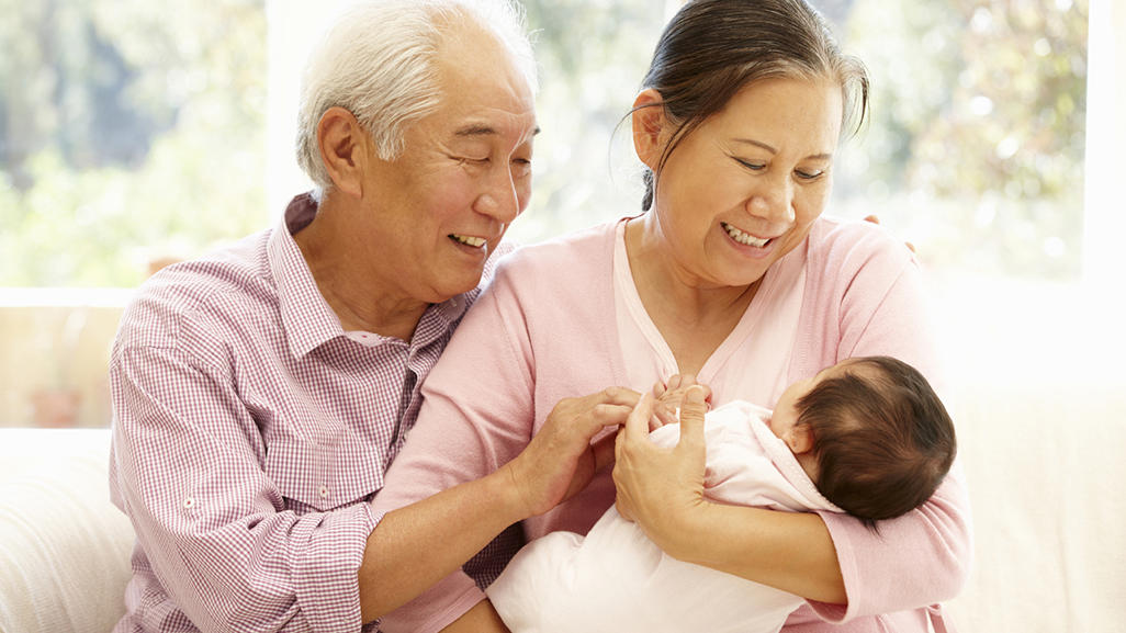 older male and female staring lovingly down at baby held in female's arms