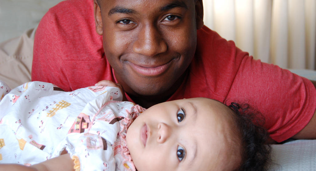 man laying next to baby smiling