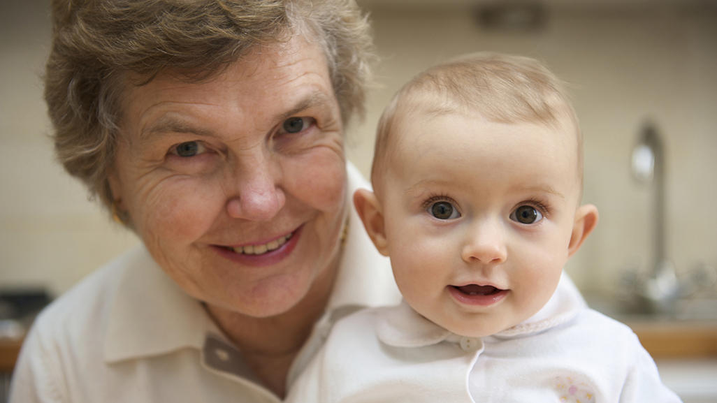 older woman holding smiling baby