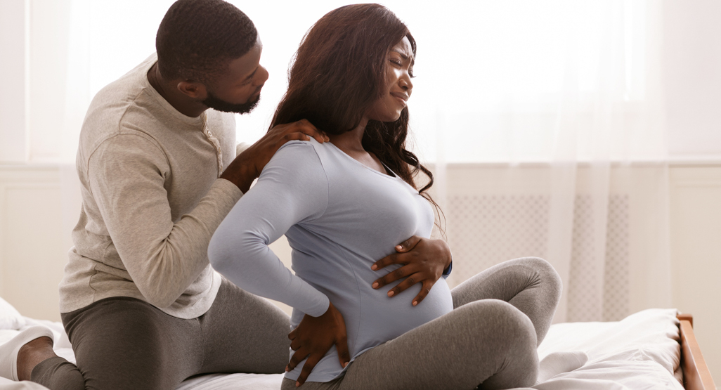 pregnant woman with back labor pain getting massage from husband