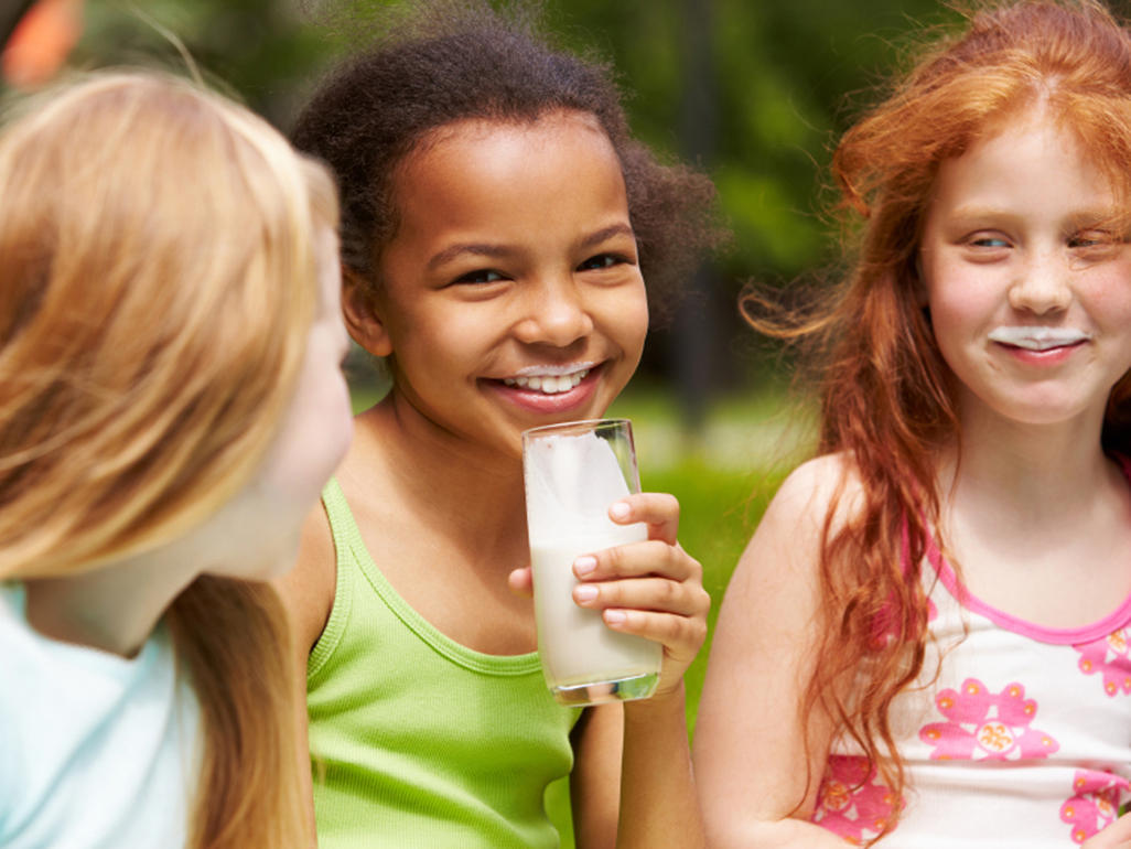 three little girls at the park drinking yogurt