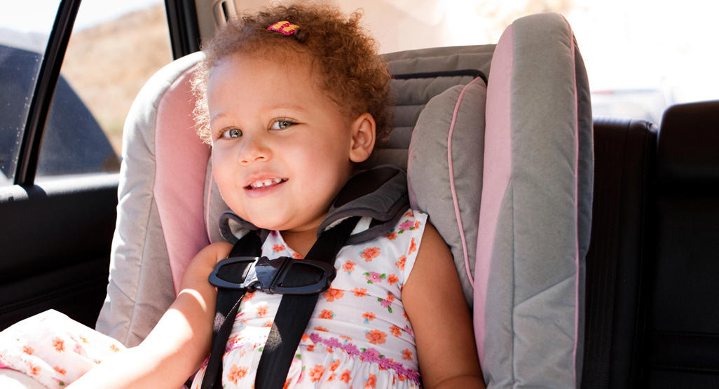 little girl sitting in car seat smiling