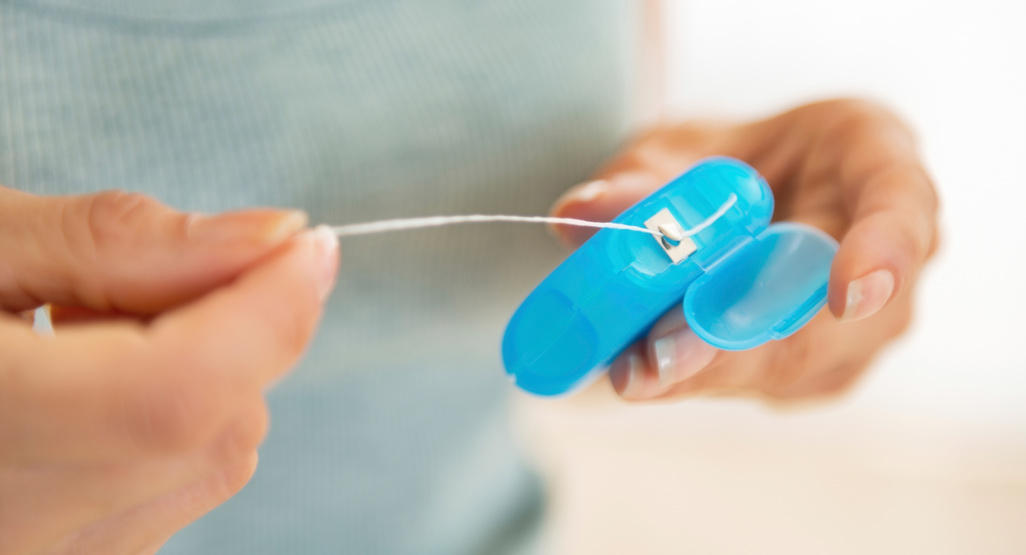 woman pulling dental floss from container