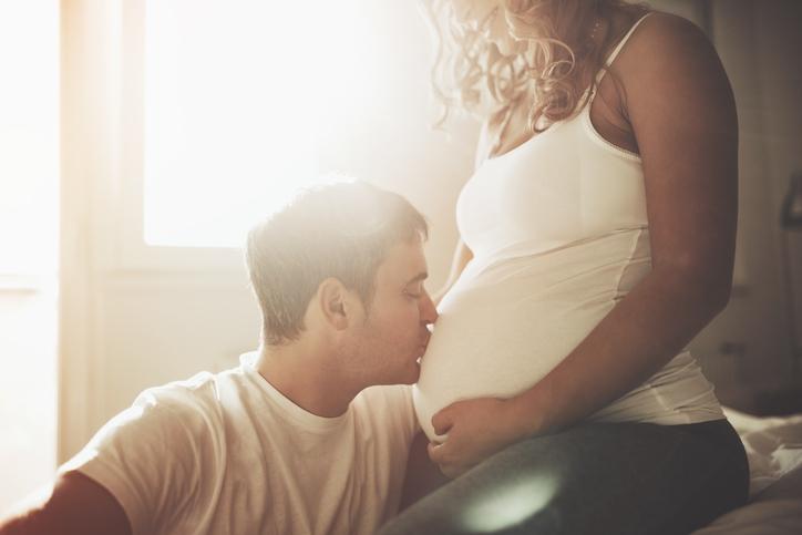 man kissing pregnant woman belly