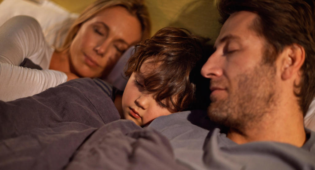 child sleeping between his parents in their bed