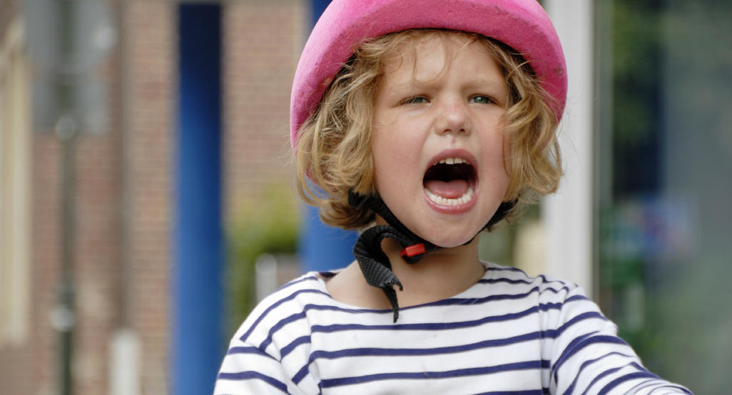 girl wearing a helmet and yelling while riding a bicycle