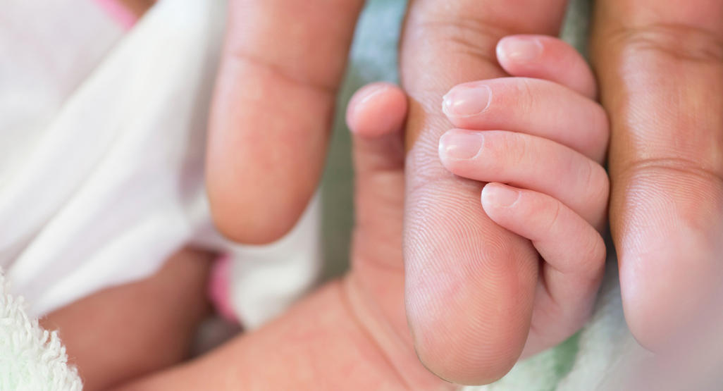 newborn closing his fist around an adults finger