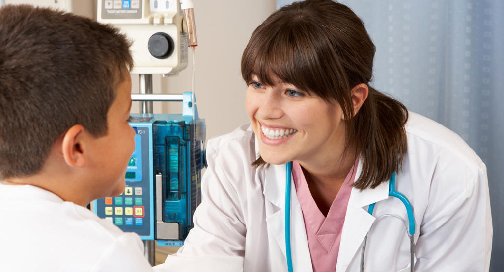 female doctor smiling and leaning towards a boy who came to do a regular health check