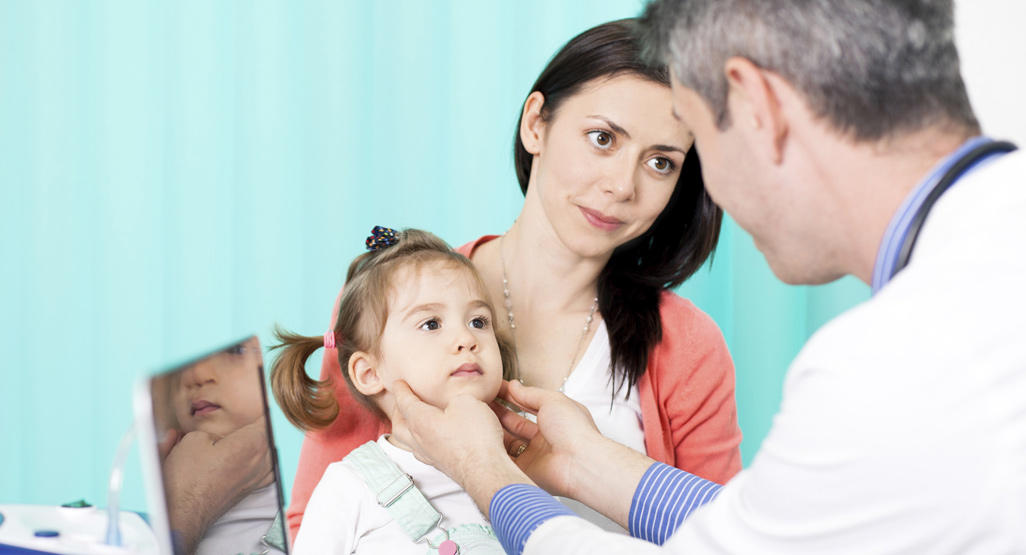 doctor examining the small girl while the mother is holding her