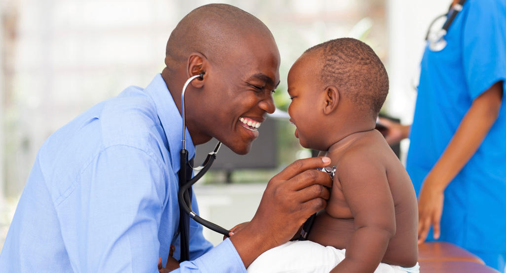 smiling doctor examining a child with a stethoscope