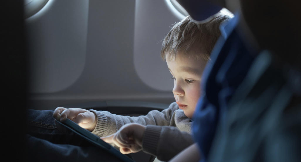 child looking at his father's smartphone at the airplane