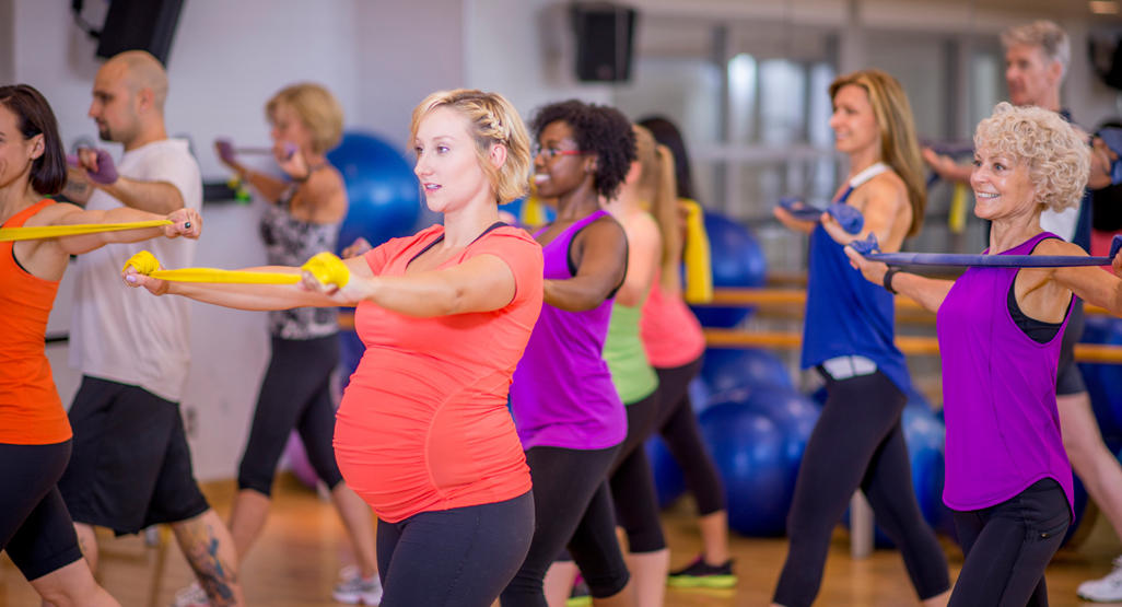 pregnant woman doing aerobics in a group at the gym