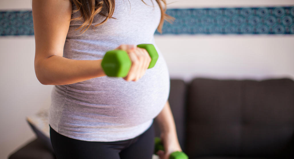 pregnant woman exercising her arms with dumbbells