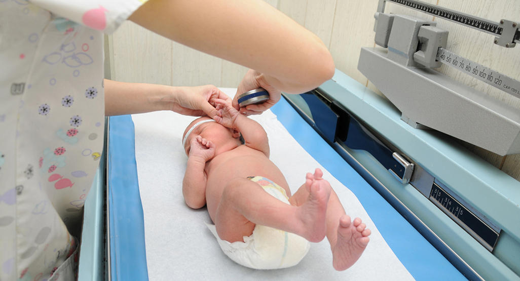 baby being measured at the clinic by a nurse