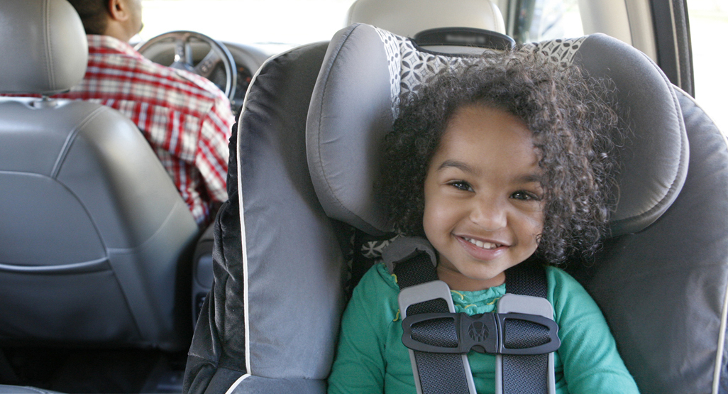 smiling toddler aged little girl rear facing in car seat