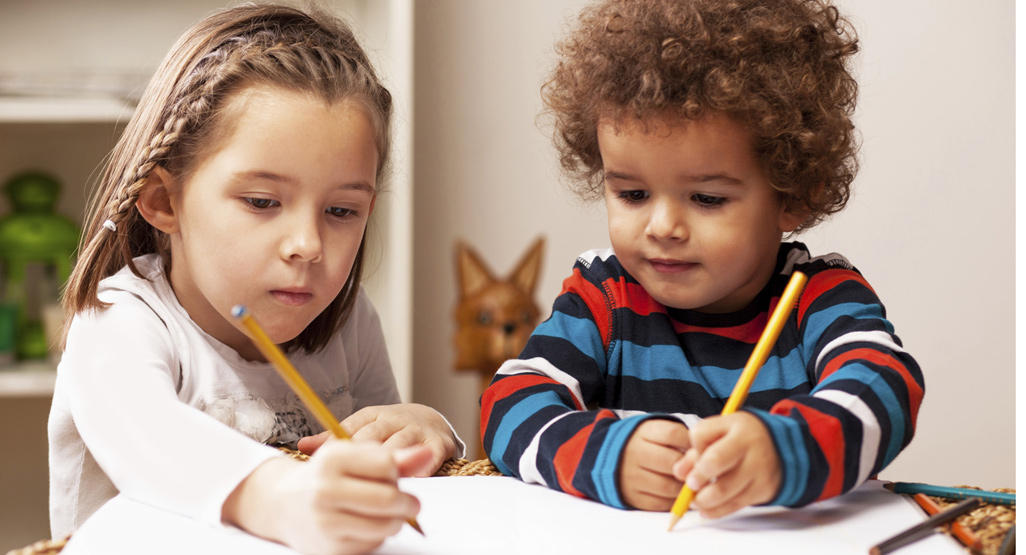 two children holding pencils and learning to write