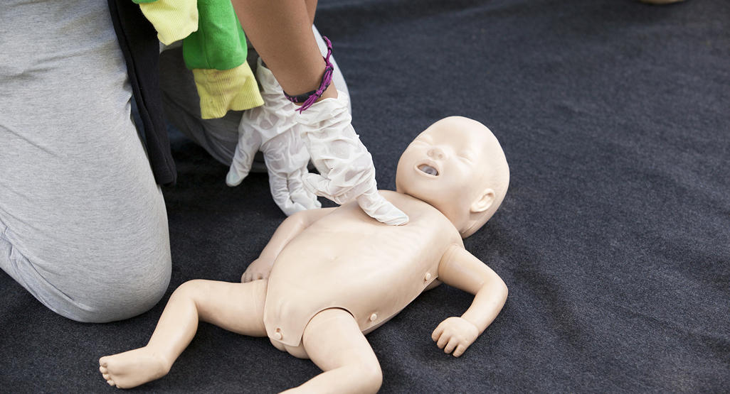 adult performing cpr on a baby doll