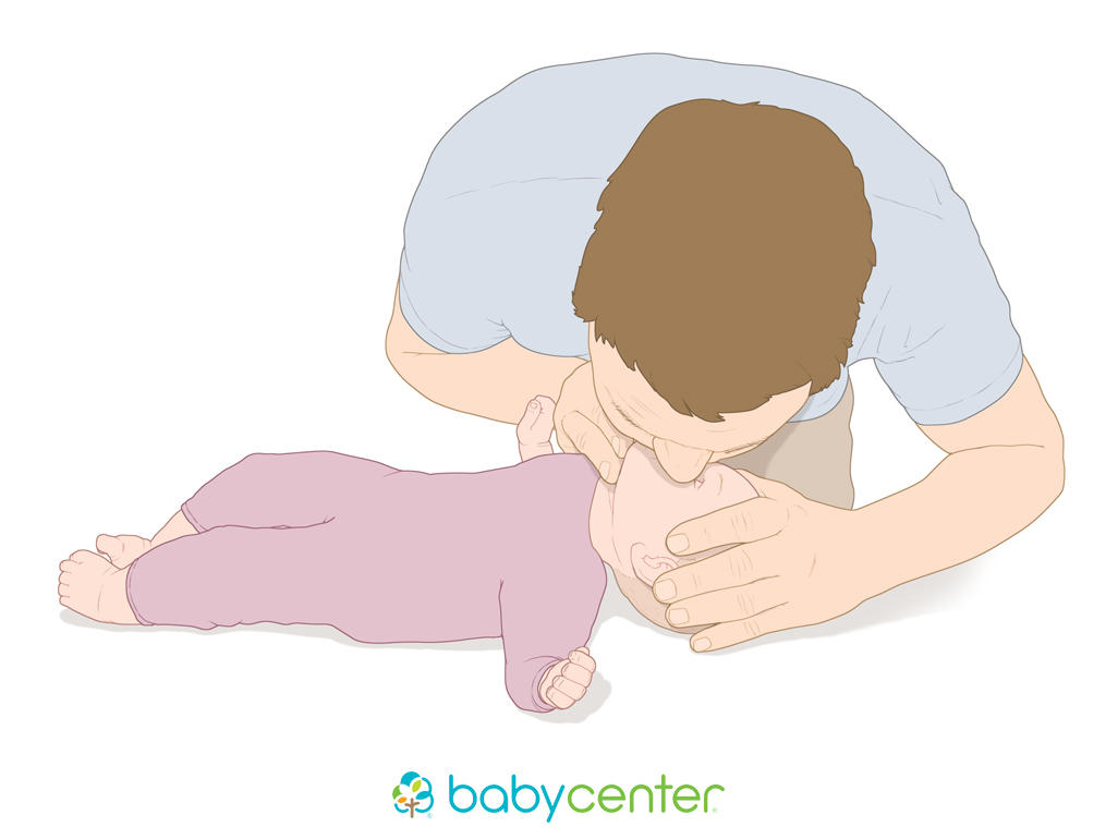 baby laying with adult over her, making lip to lip contact, one hand pushing back the forehead and the other hand pushing up the chin
