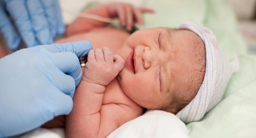 doctor wearing medical gloves holding a newborn baby with