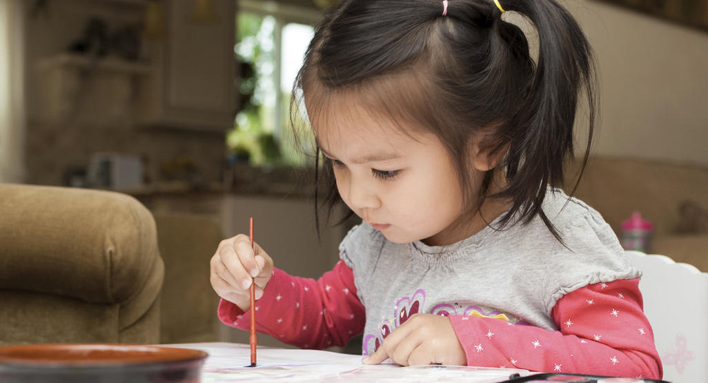 child sitting and doing watercolor painting