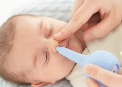 baby having a bulb syringe put into nostril by adult