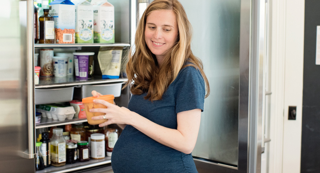 pregnant woman taking food out of the fridge