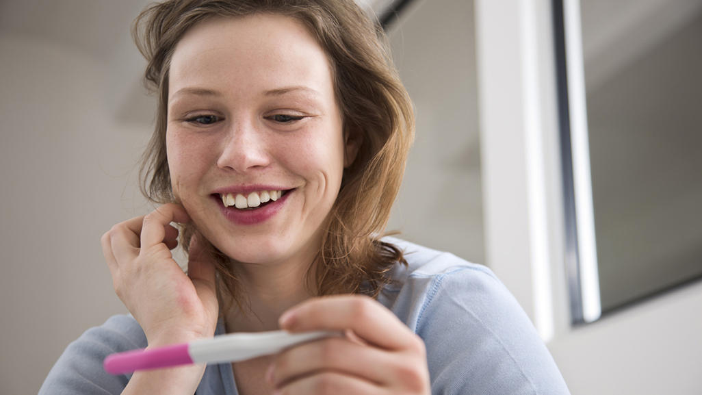 smiling woman looking at the pregnancy test