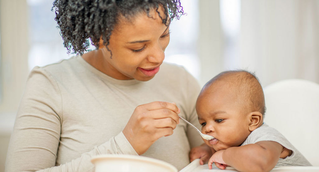 Mom spoon feeding baby a rice cereal