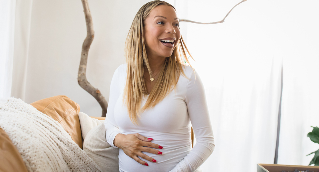 pregnant woman laughing while holding belly
