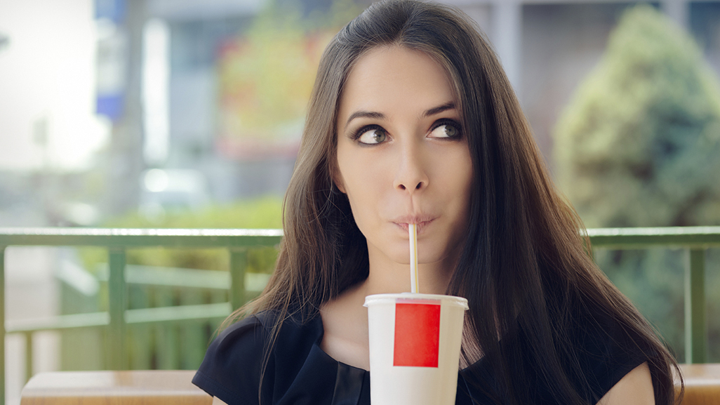 woman drinking from a cup with a straw