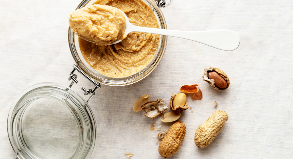 jar of peanut butter with crushed peanuts on the side