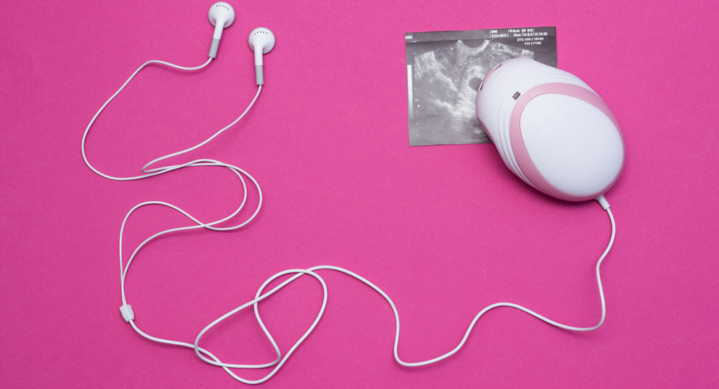 fetal doppler with earphones on pink surface