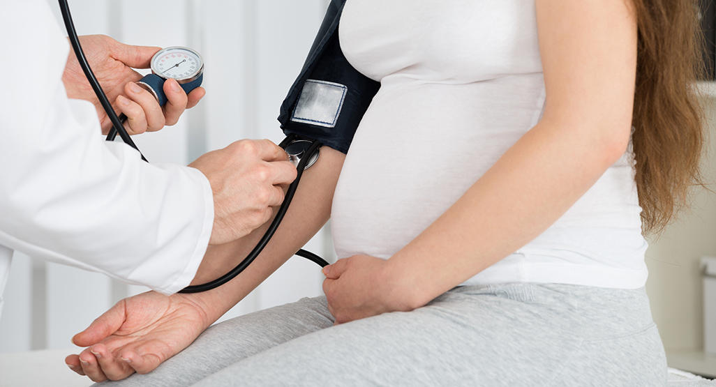 doctor measuring blood pressure of a pregnant woman