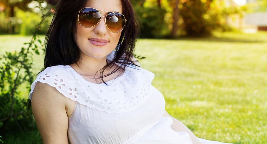 pregnant woman sitting on grass on a bright sunny day