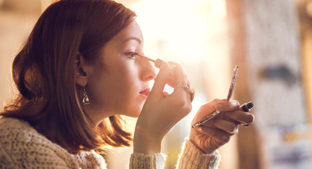 woman applying makeup to her eyes