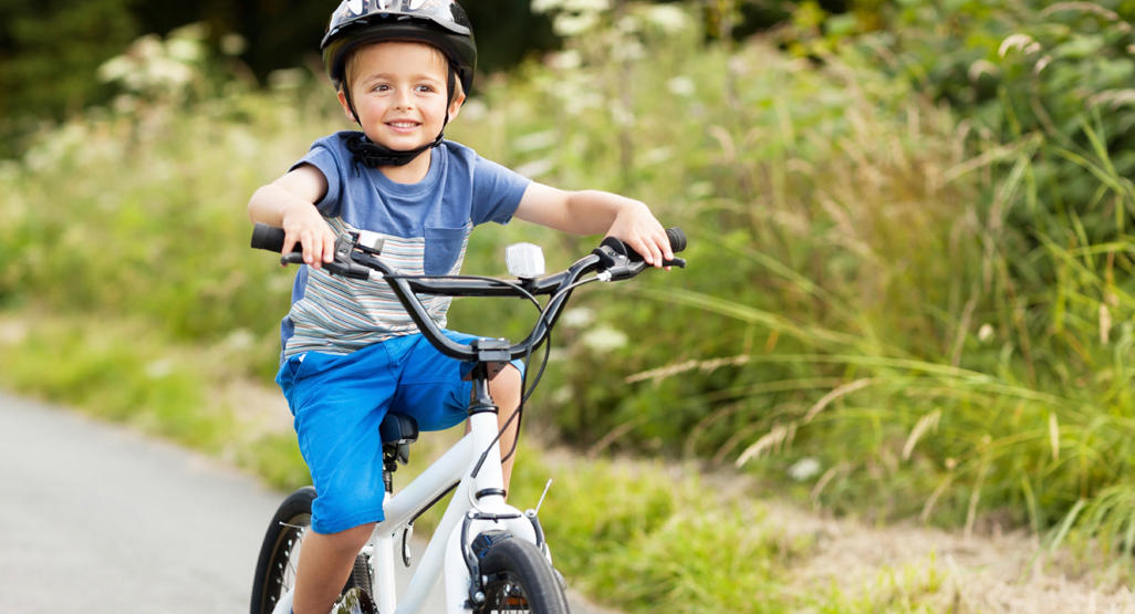 child riding a bicycle with a helmet on his head
