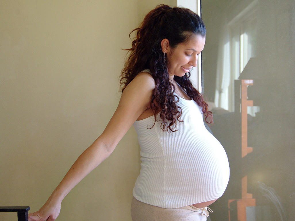 pregnant woman in tank top standing in the hallway of a house