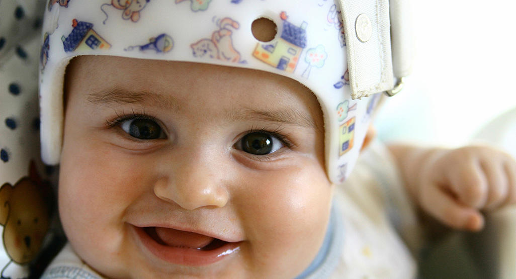 smiling baby wearing a safety helmet