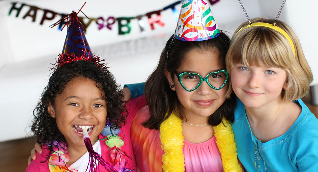 three school aged girls celebrating a birthday while wearing birthday hats and fun glasses